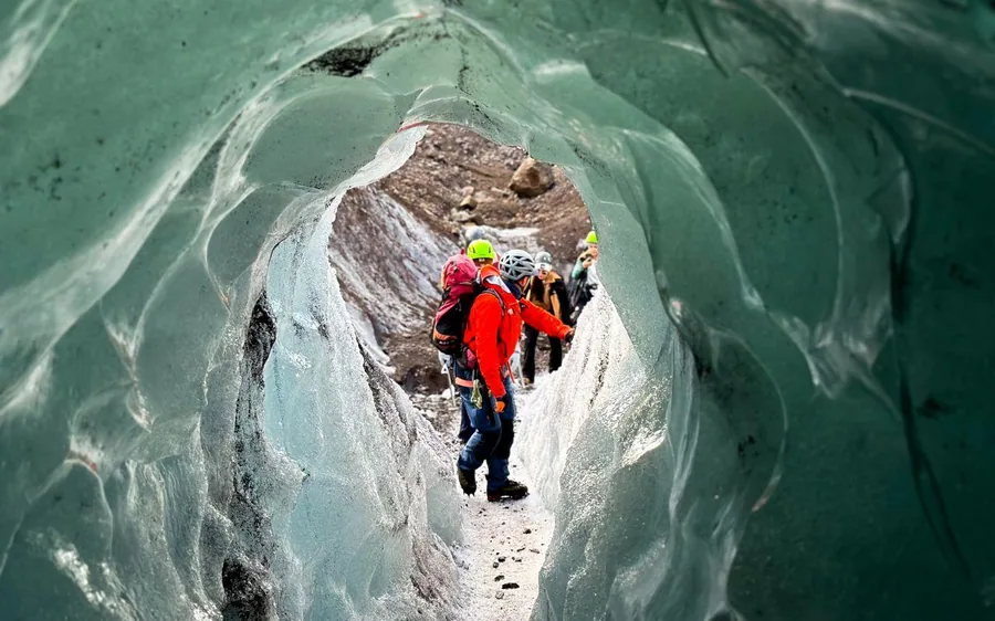 People inside a blue ice cave reached on a glacier hike at Skaftafell, Iceland