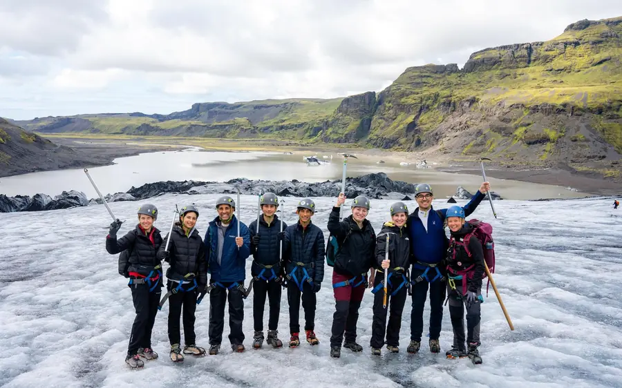 A group in helmets and crampons beside a glacier in south Iceland
